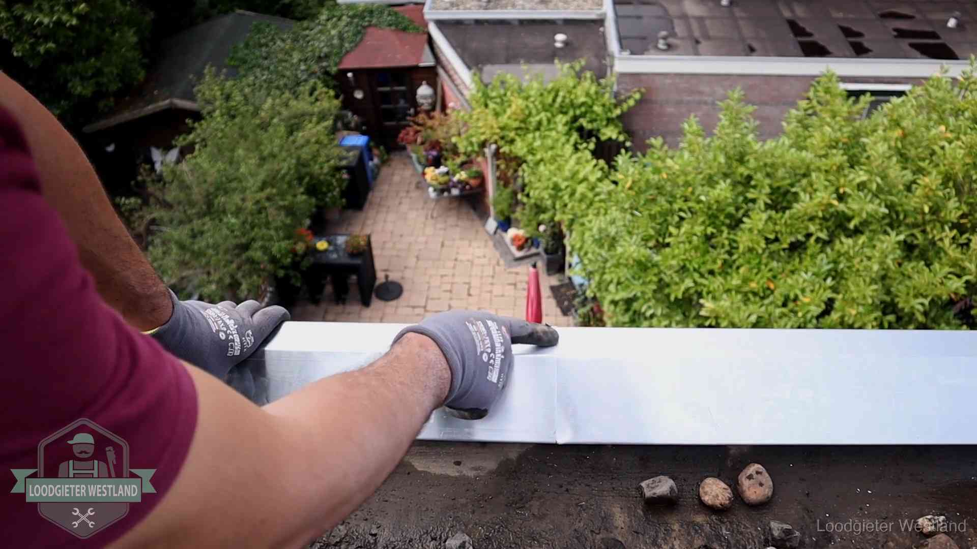 Daklekkage geregeld in Westland Vakman plaatst een daktrim op de dakrand van een woning in Westland