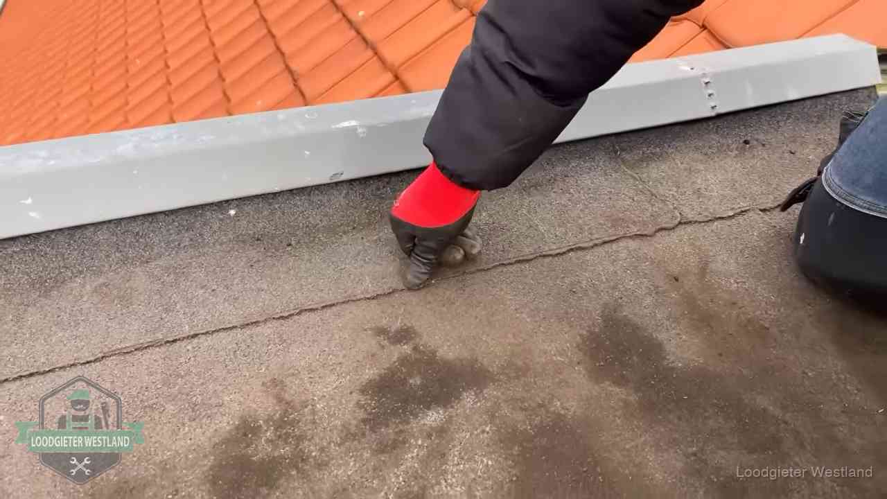 Lekkage bij de naad van een plat dak in Westland Vakman wijst een naad met vochtplekken aan op een bitumen plat dak in Westland