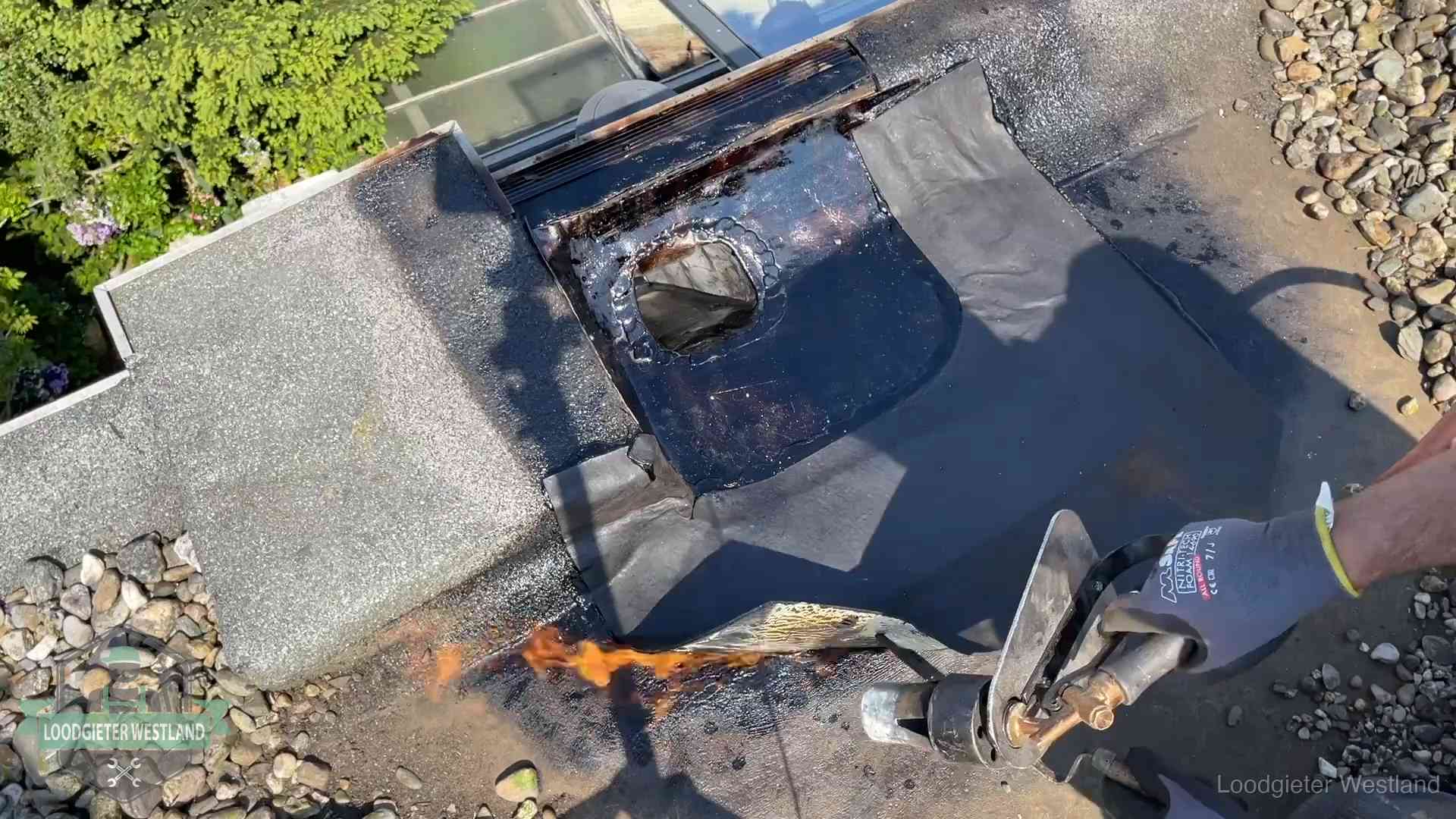 Daklekkage repareren in Westland Dakdekker brandt bitumen rond een doorvoer tijdens een daklekkage-reparatie in Westland