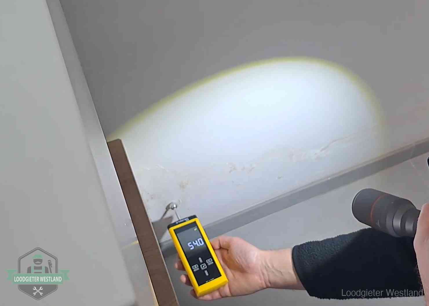 Vochtmeter tegen een natte wand met lekkagesporen in Westland