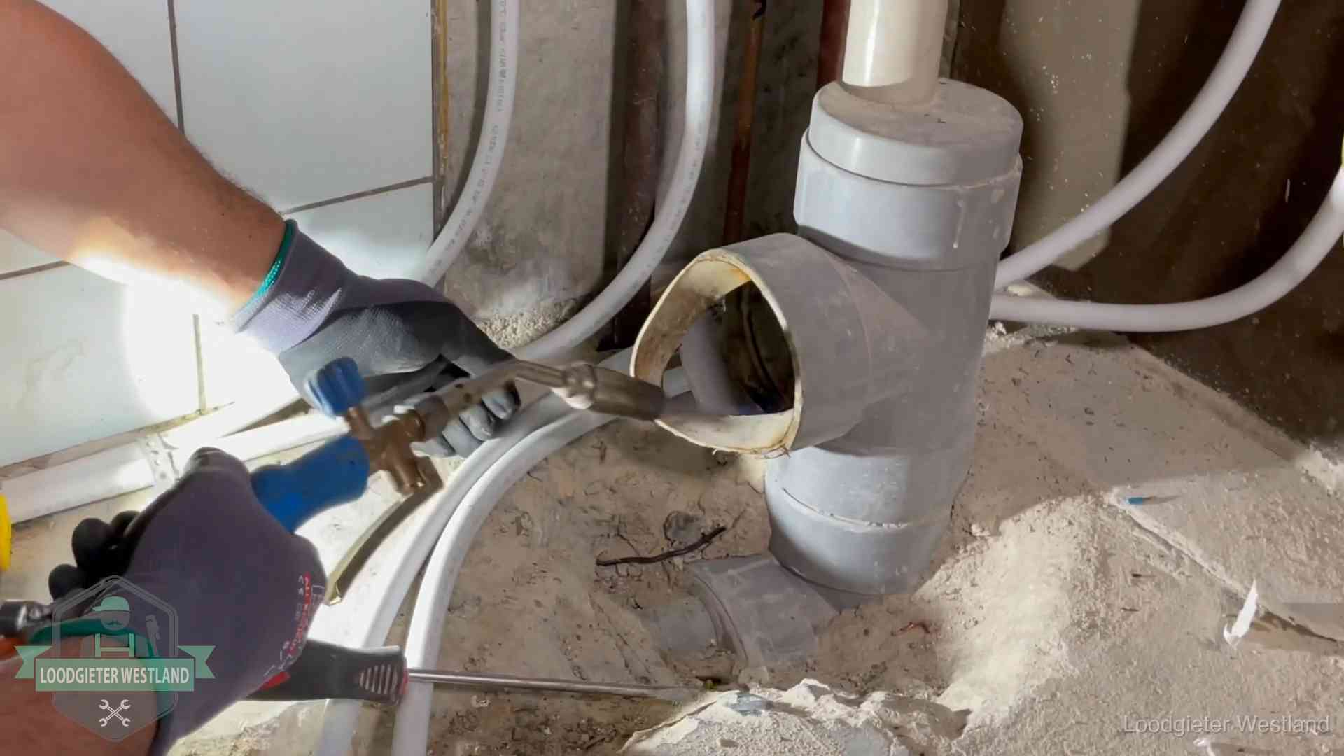 Loodgieter werkt met brander en messing kraanwerk aan leidingen in Westland