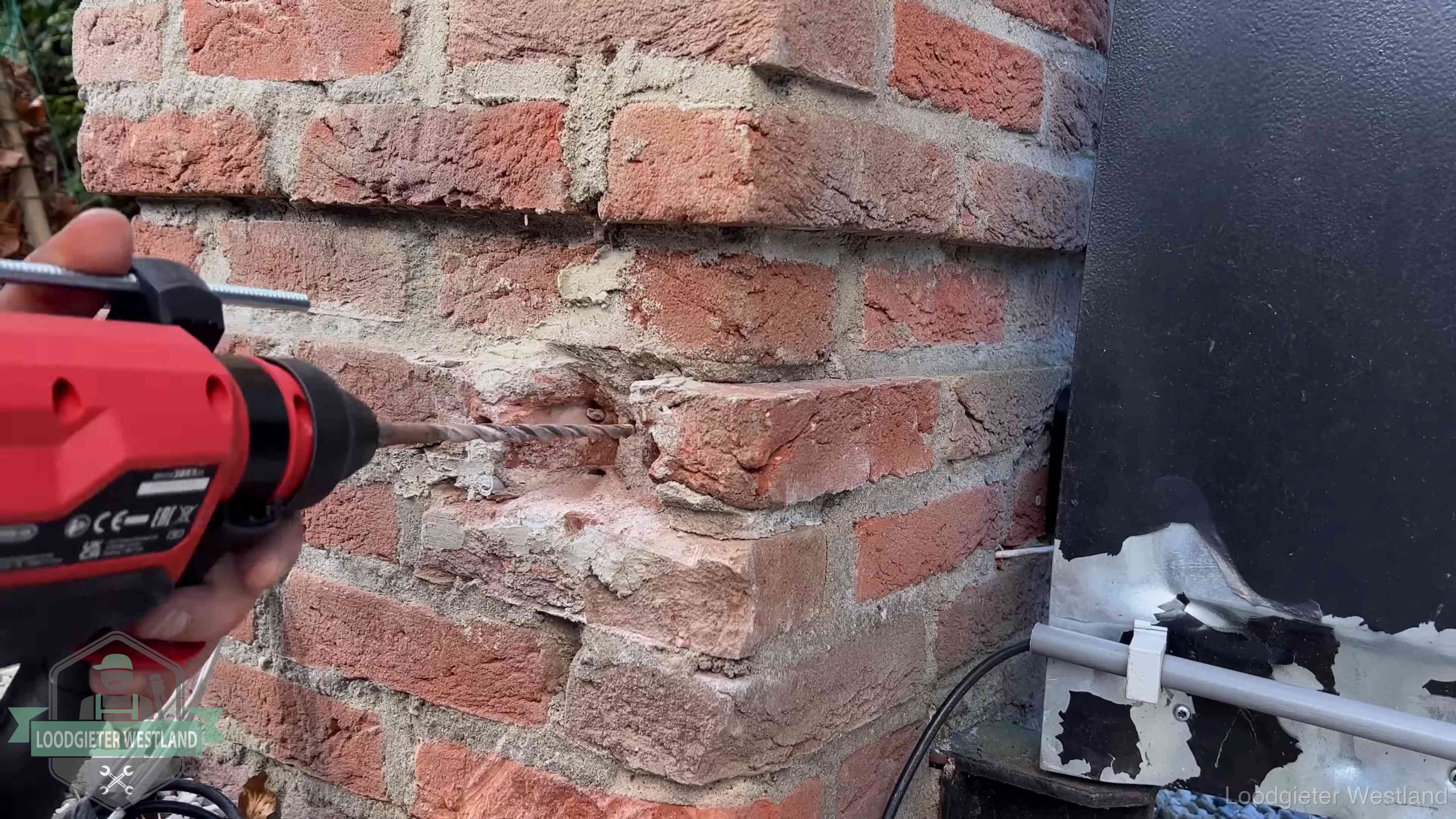 Vakman boort in de buitenmuur van een woning in de regio Westland