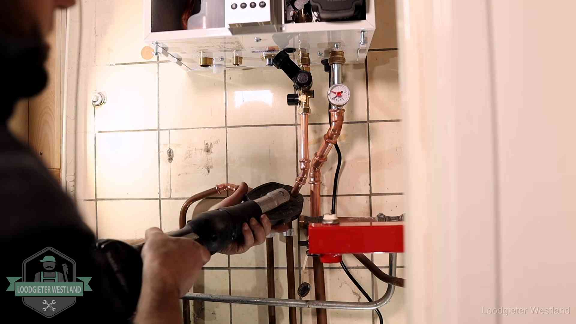 Monteur werkt aan de leidingen onder een cv-ketel in Westland