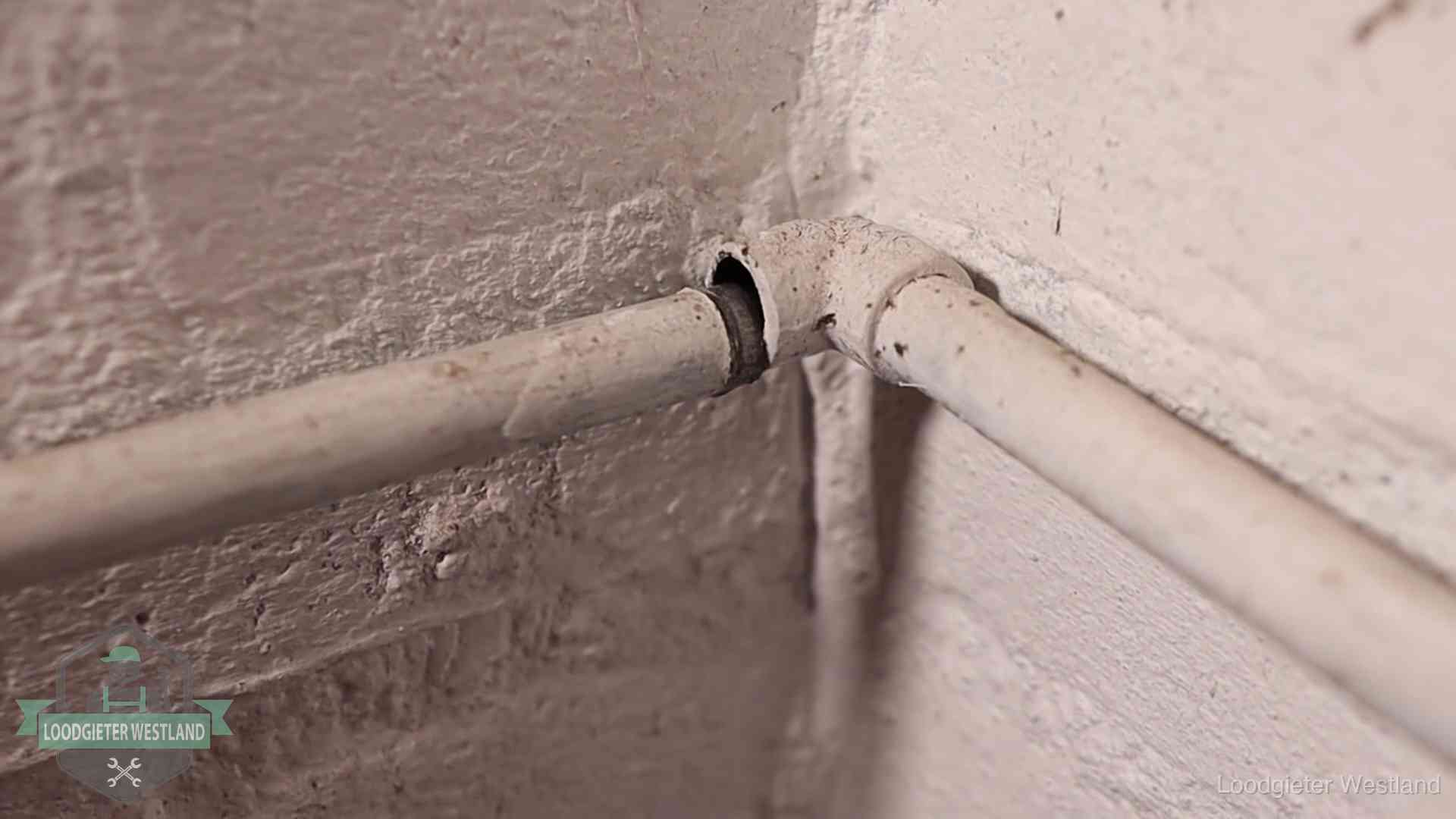 Oude geverfde waterleiding met een losliggende fitting in een woning in Westland