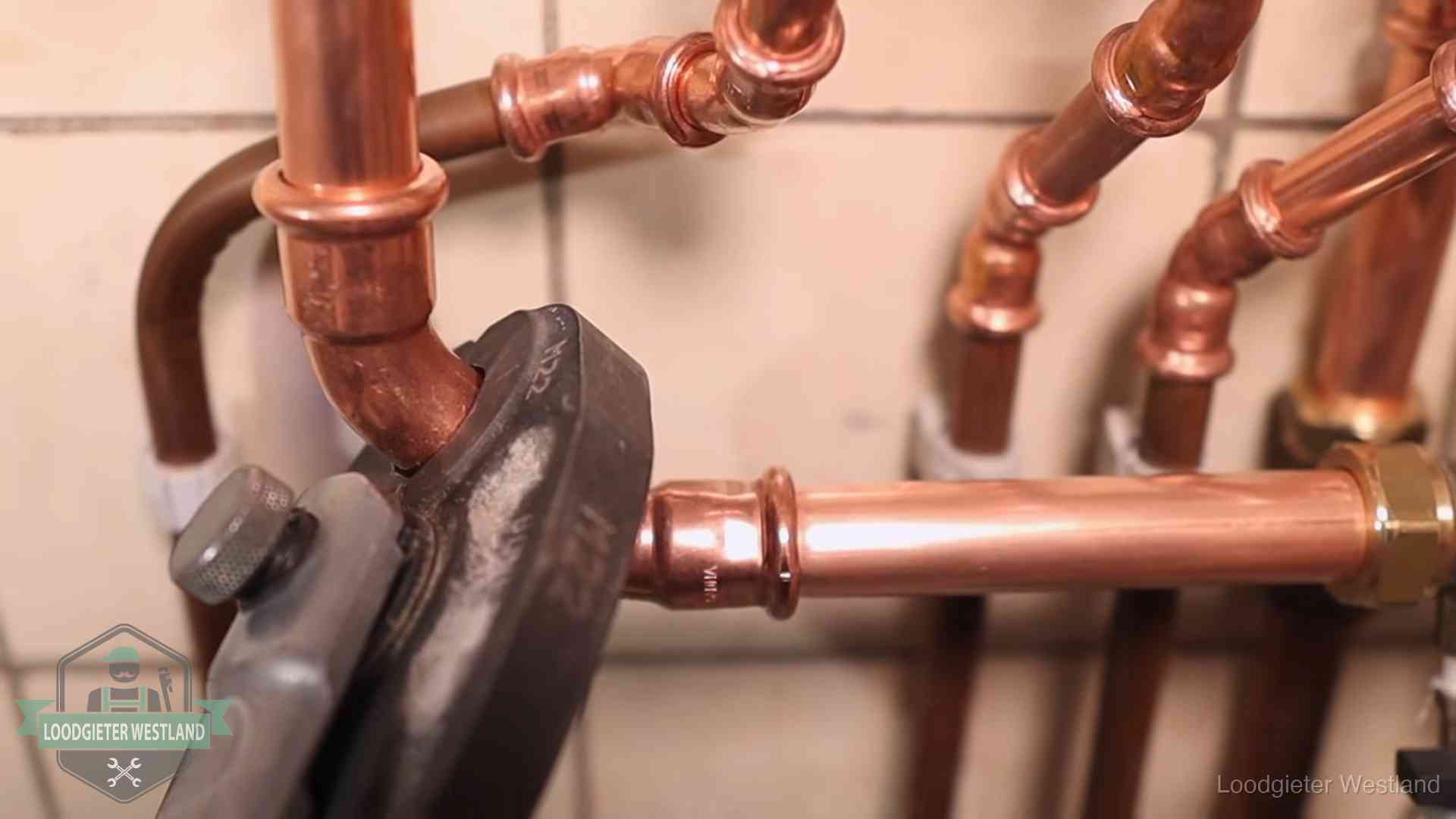 Persmachine perst een koperen fitting op nieuw leidingwerk in Westland
