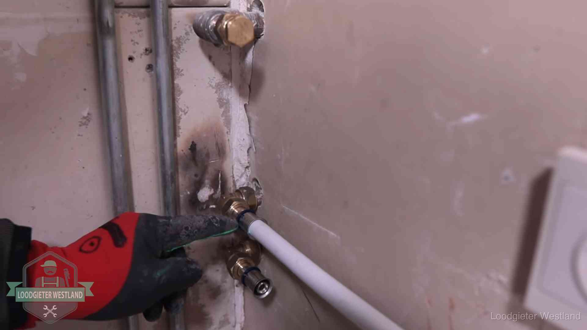Loodgieter wijst de persfitting op nieuwe muuraansluitingen aan in een woning in Westland