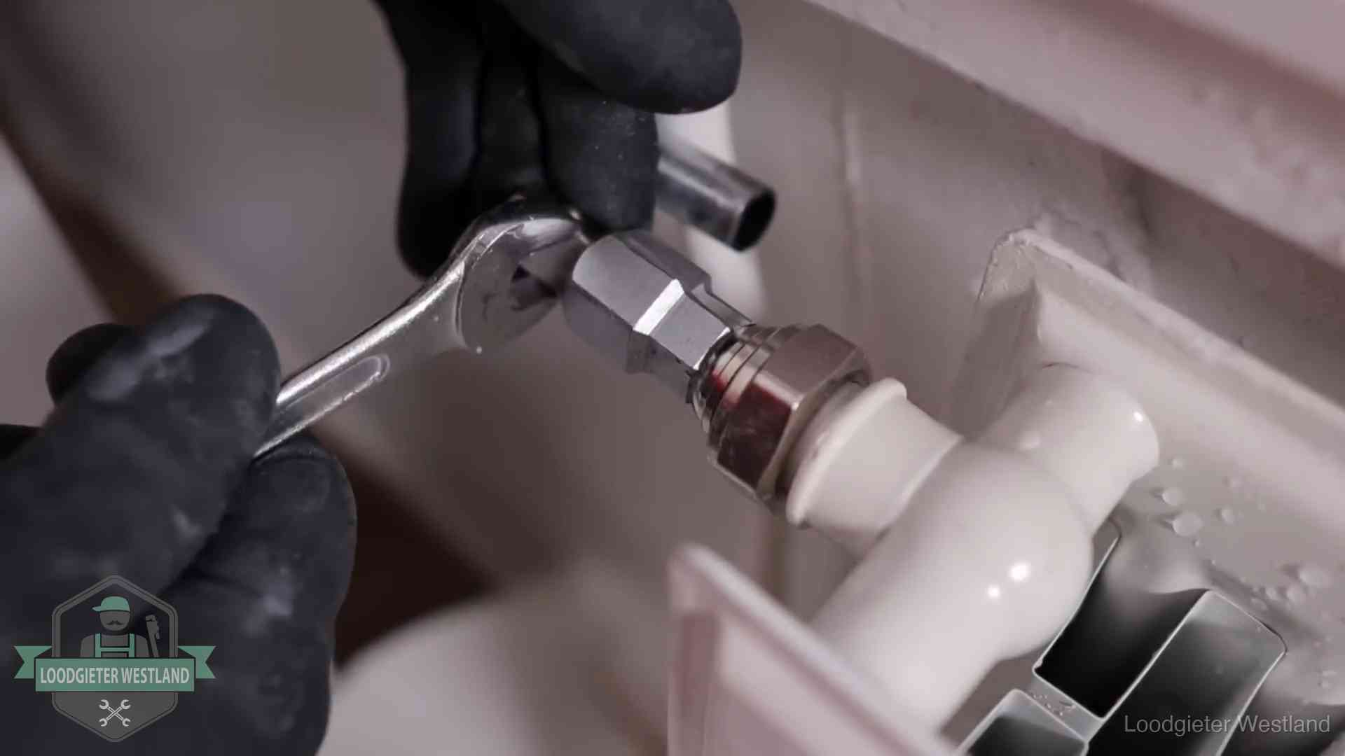 Steeksleutel draait een wartelkoppeling op een radiatorkraan aan in Westland