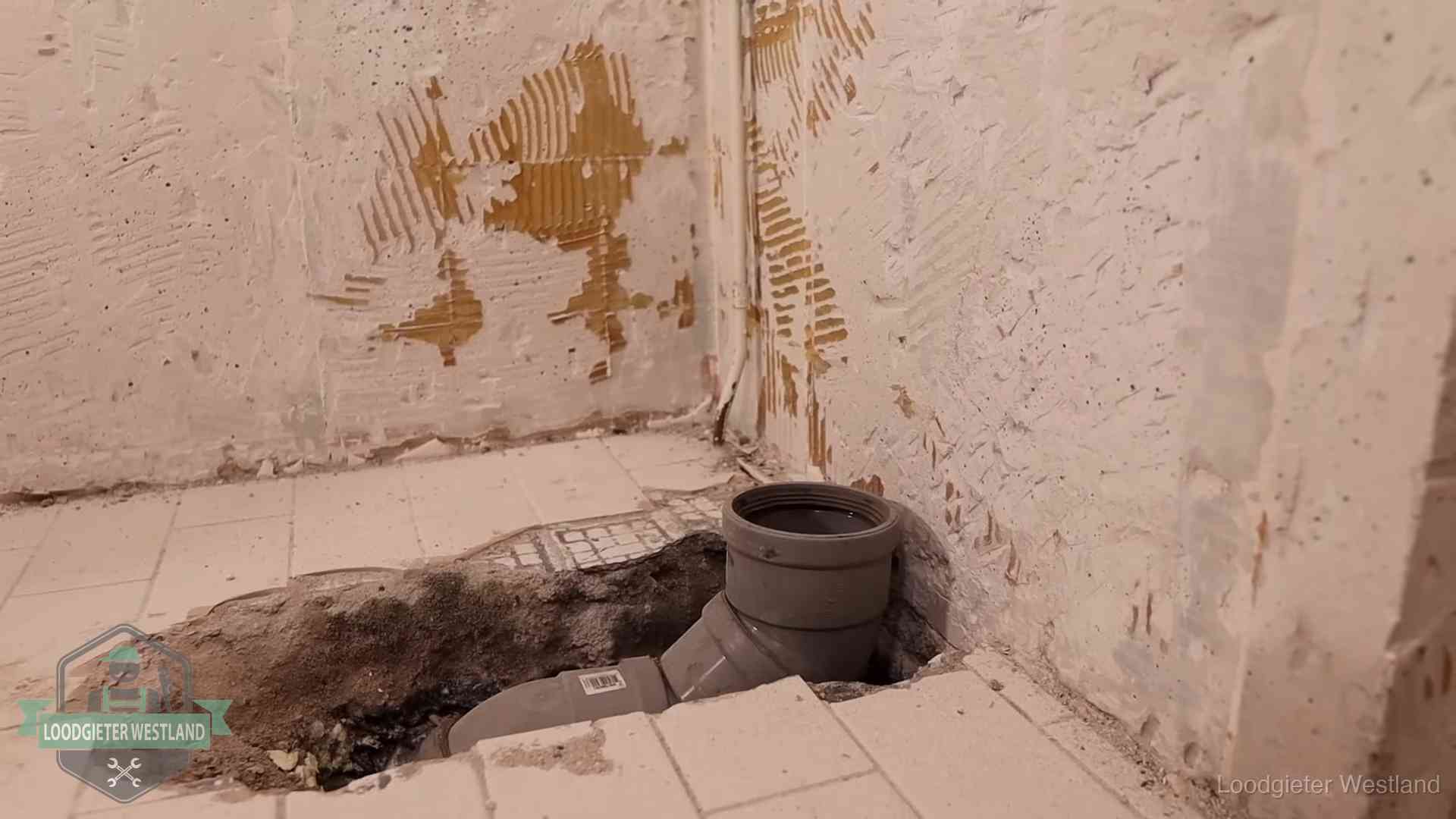 Verzakt riool herstellen in Westland Opengebroken vloer met een nieuwe pvc-rioolbocht in een gegraven sleuf in Westland