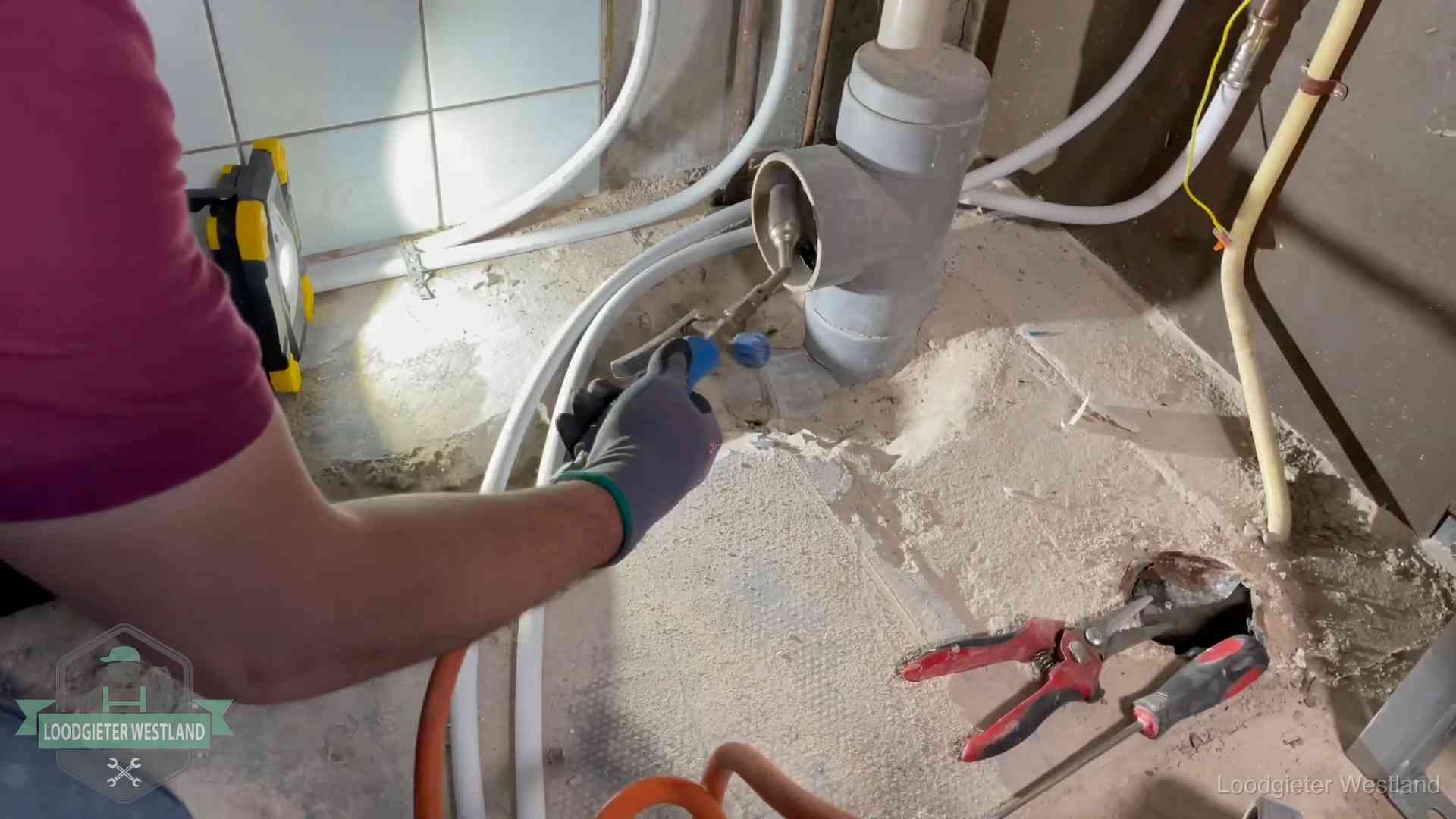 Loodgieter werkt aan leidingen bij een pvc-standleiding in een appartement in Westland
