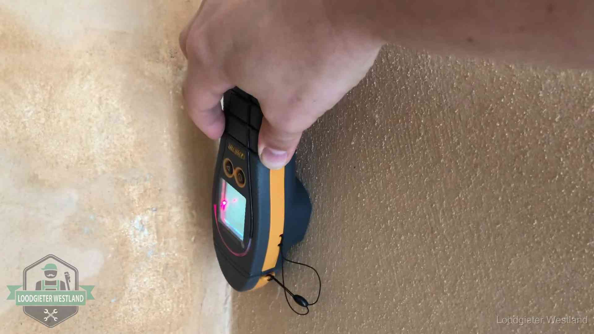 Daklekkage opsporen zonder hakwerk in Westland Vochtmeter tegen een muur met vochtplekken tijdens het opsporen van een daklekkage in Westland
